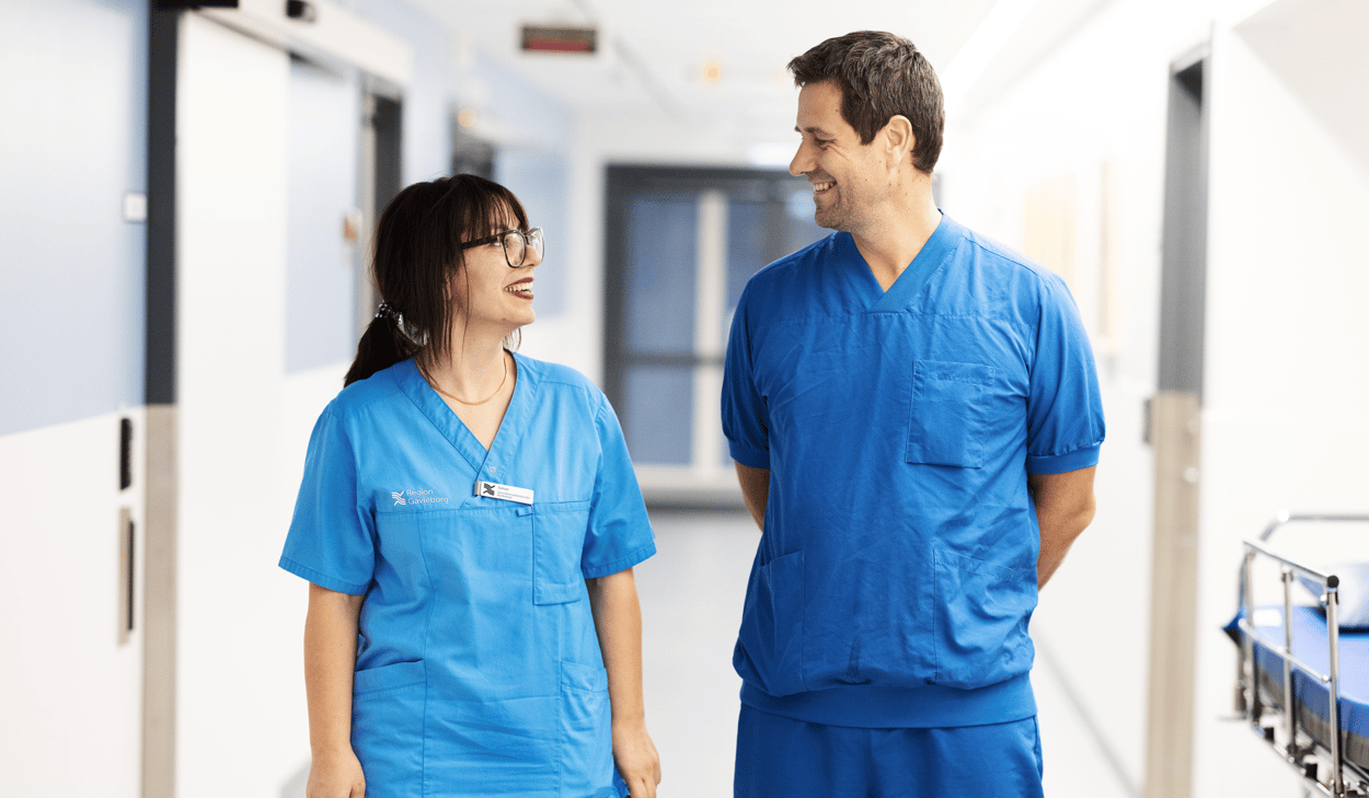 En man och en kvinna i som står i en sjukhuskorridor.