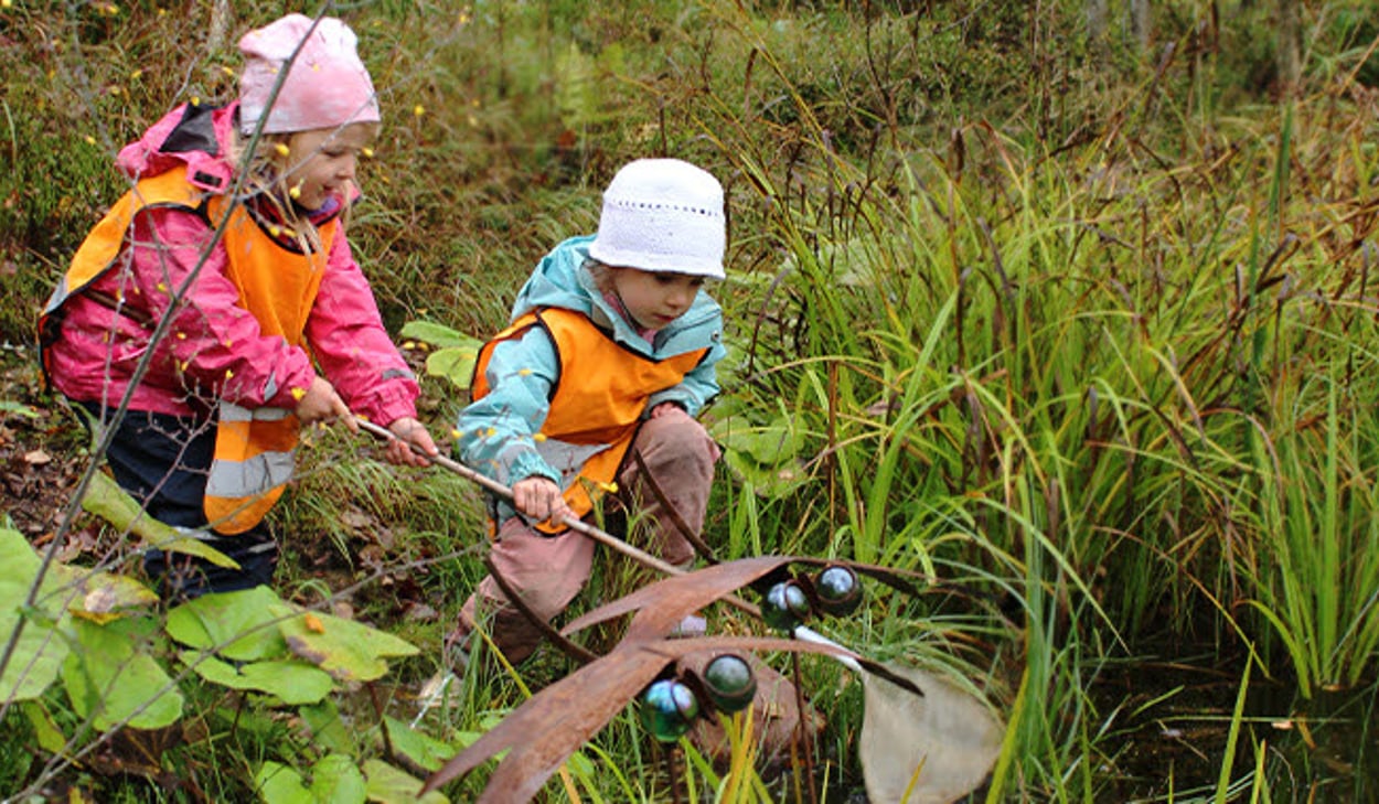 Två barn leker i naturen