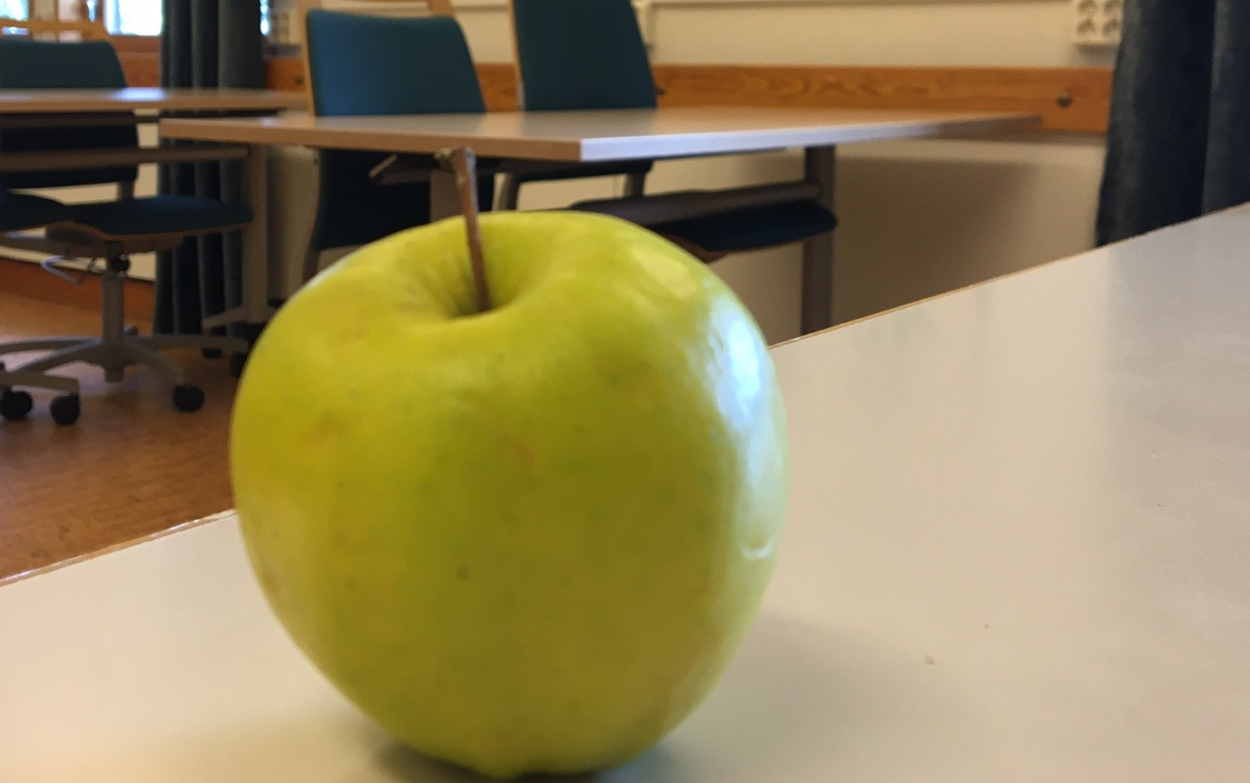 Ett grönt äpple som ligger på en vit bänkskiva.