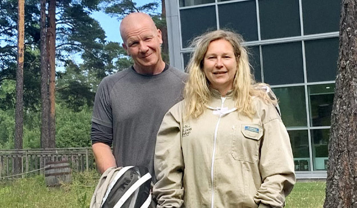 En man och en kvinna står i ett skogslandskap och tittar leendes in i kameran.