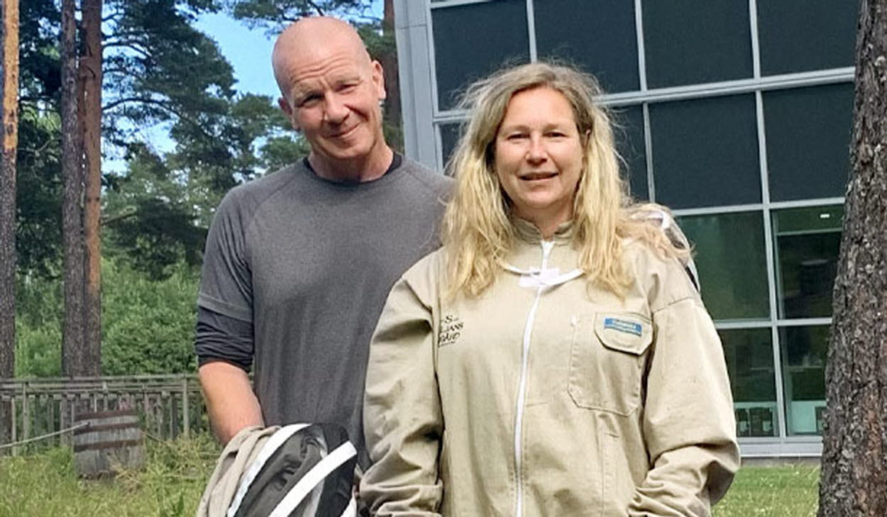 En man och en kvinna står i ett skogslandskap och tittar leendes in i kameran.