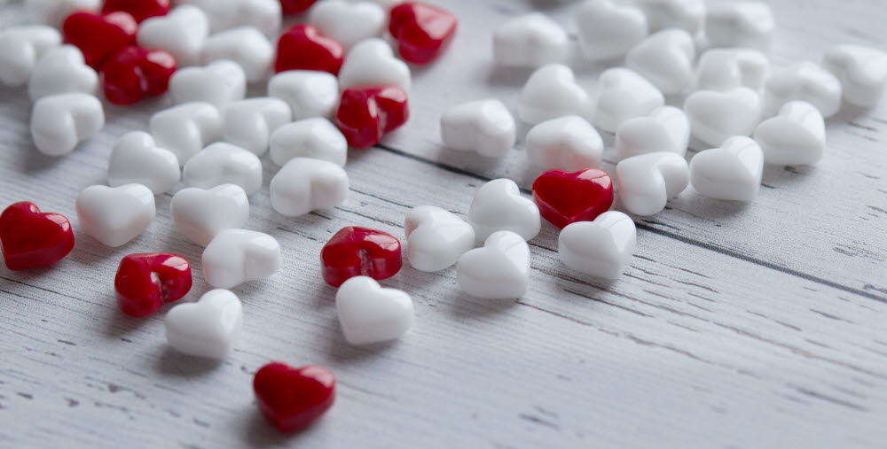 Foto på röda och vita små hjärtan som ligger på ett bord.