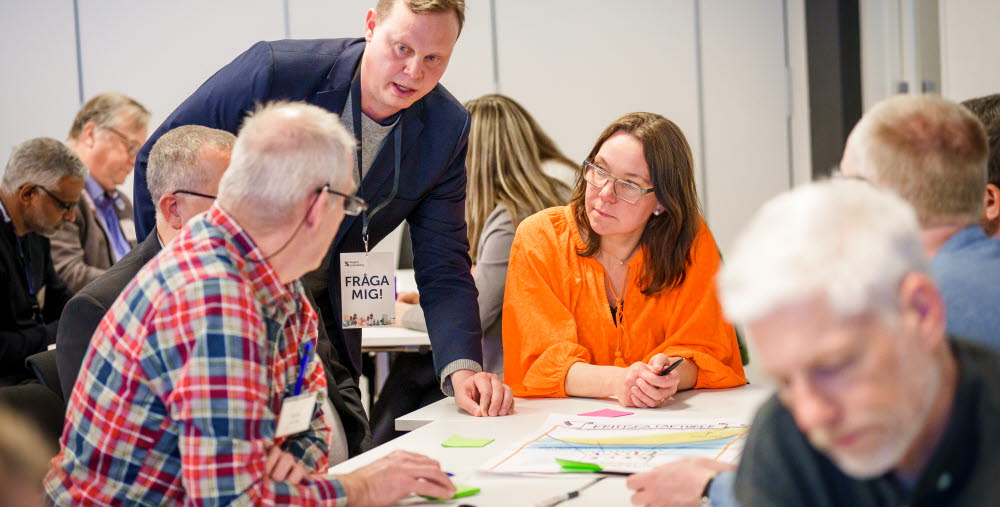Flera personer samarbetar i samtal runt ett bord.